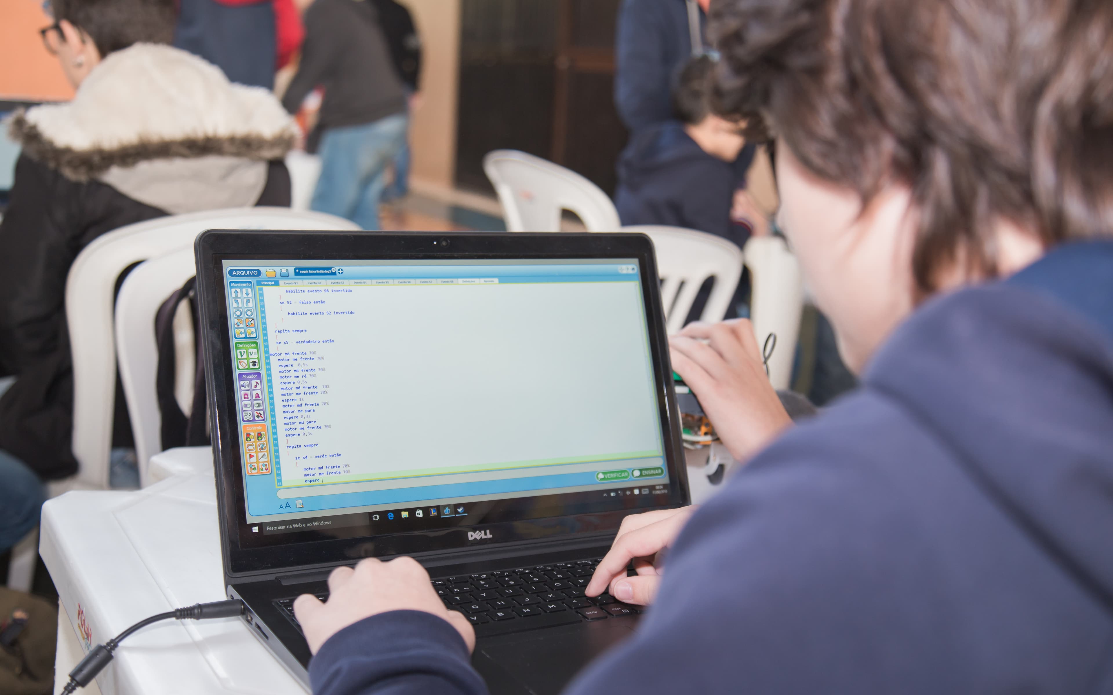 Estudante programando o robô no LEGAL, ambiente de blocos em tela de notebook
